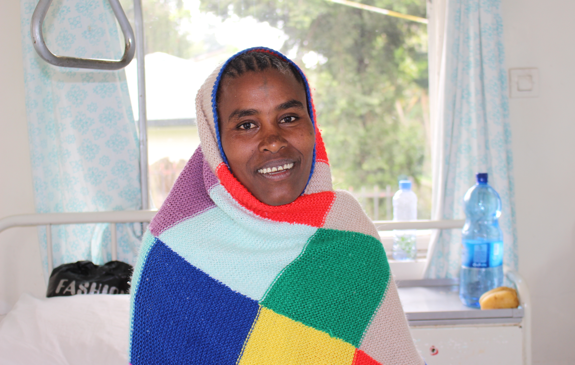 Mulu wrapped in a blanket, smiling in the hospital ward